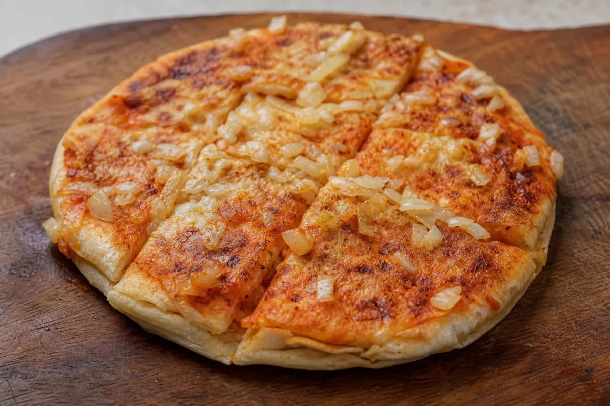Golden-brown stuffed flatbreads filled with tomato and onion, garnished with fresh herbs.
