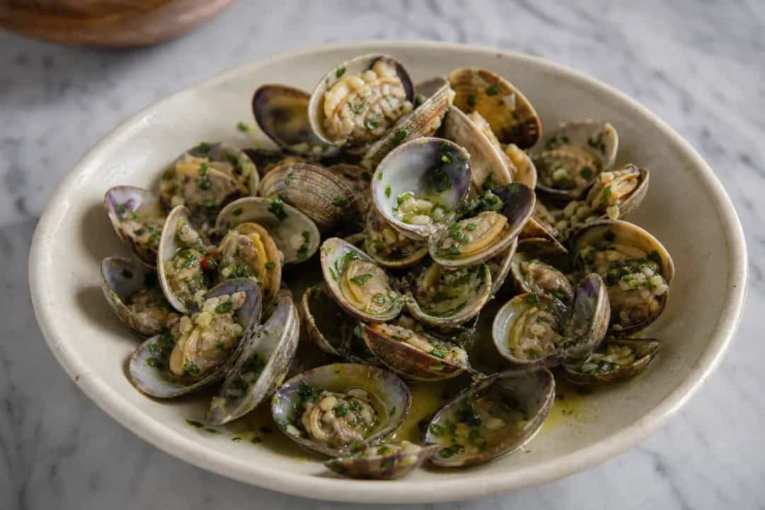 Succulent garlic clams garnished with parsley, served in a rustic bowl.