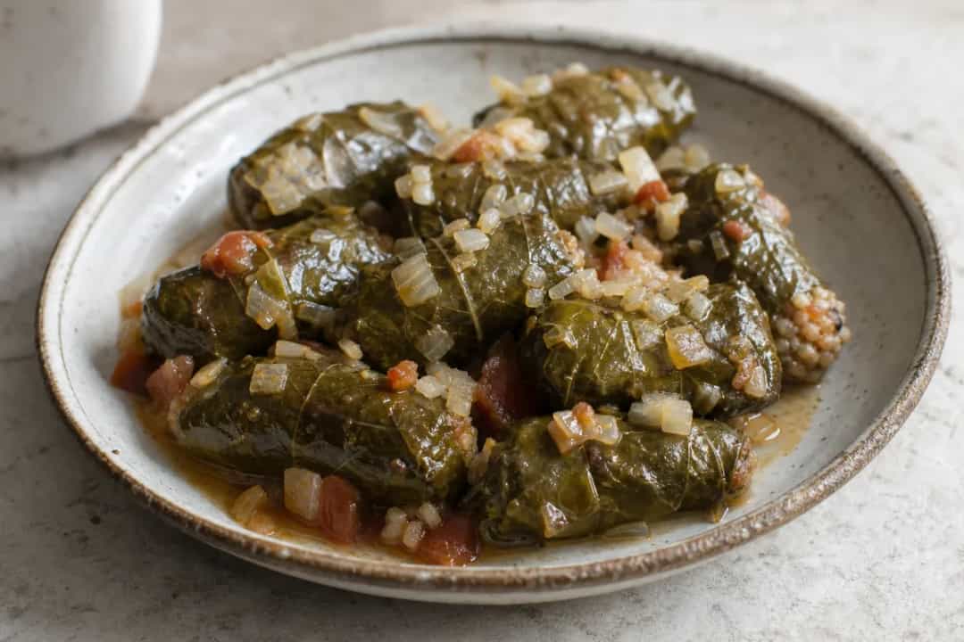 Tender grape leaves wrapped around a savory beef and rice filling, elegantly plated.