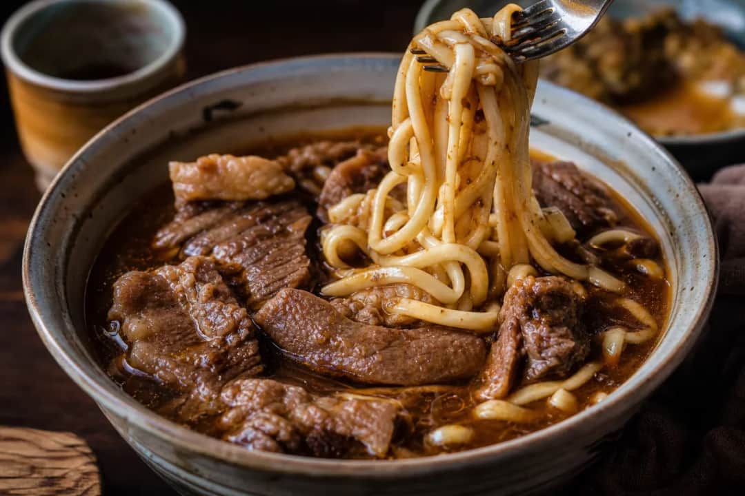 Bowl of Taiwanese beef noodle soup with tender beef, green onions, and noodles in rich broth