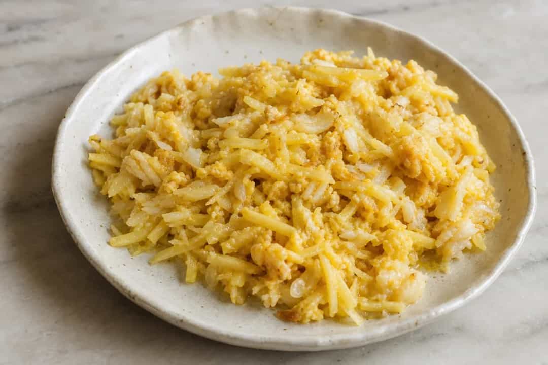 Plate of Bacalhau à Brás featuring golden potatoes, cod flakes, and a sprinkle of parsley.
