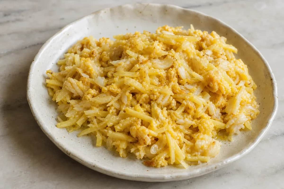 Plate of Bacalhau à Brás featuring golden potatoes, cod flakes, and a sprinkle of parsley.