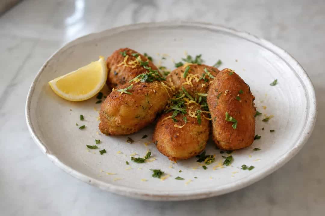 Golden brown shrimp croquettes garnished with fresh parsley and lemon wedges.