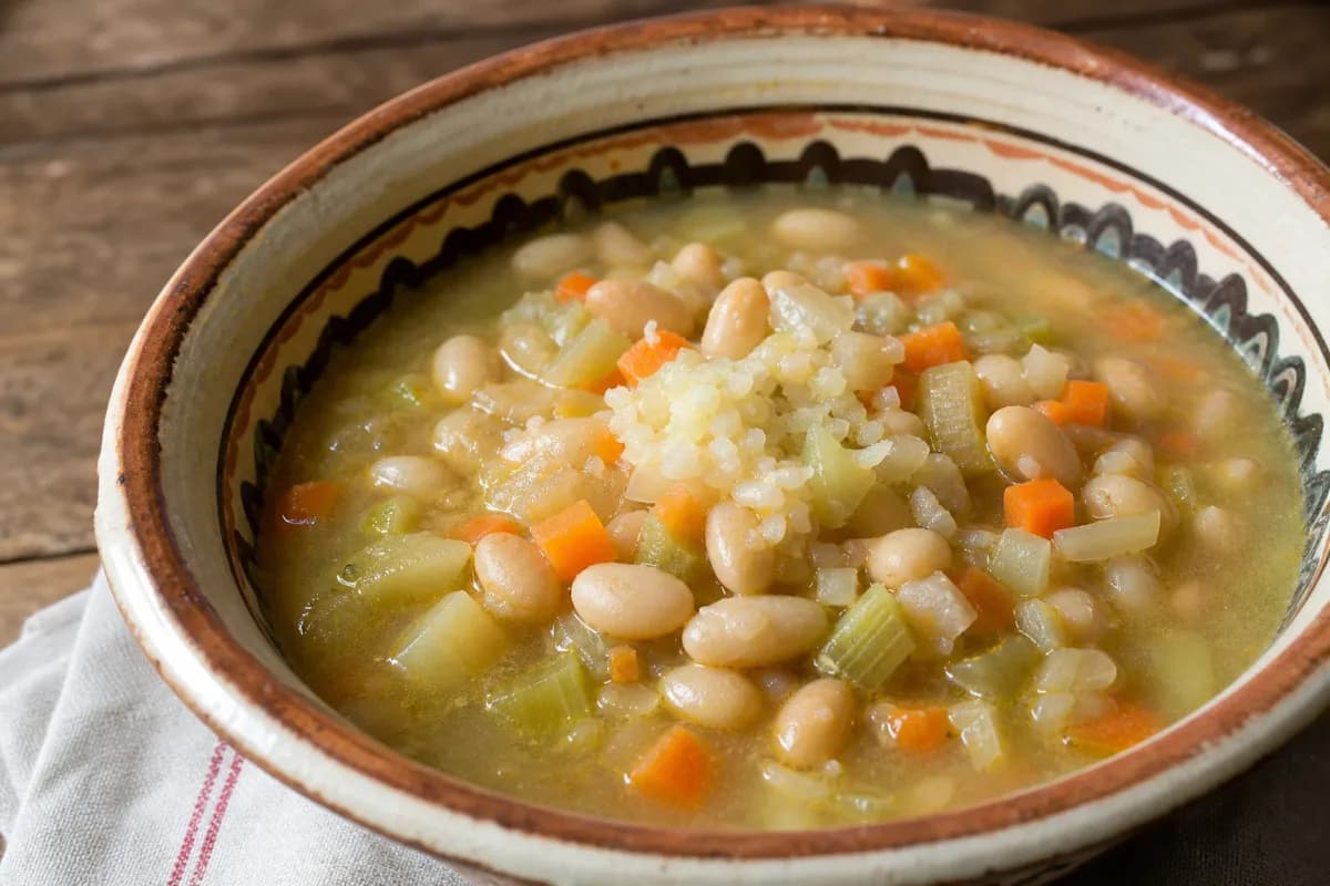 Creamy white bean soup garnished with fresh parsley and vegetables, served in a bowl.