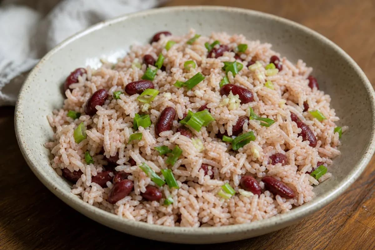 Fluffy rice and peas garnished with herbs, served in a white bowl with coconut milk texture.