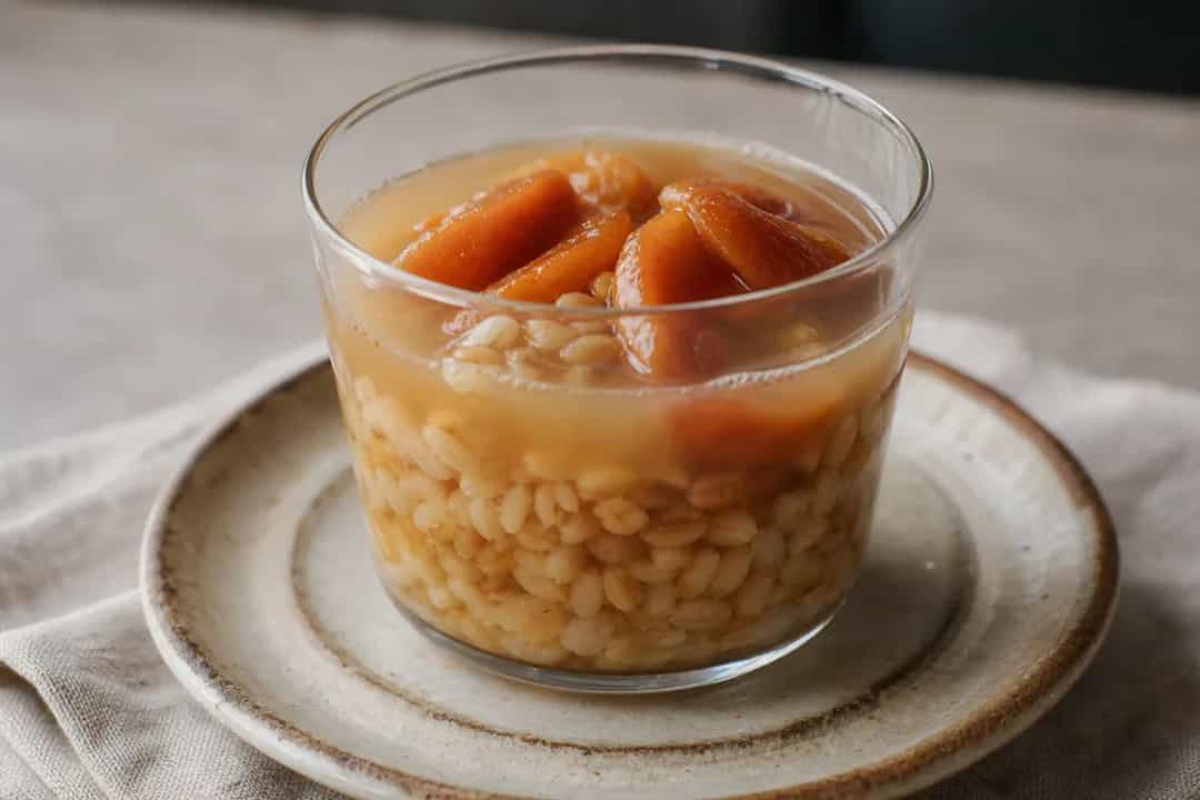 Chilean Mote con Huesillo served in a glass with peaches and wheat, showcasing a vibrant presentation.