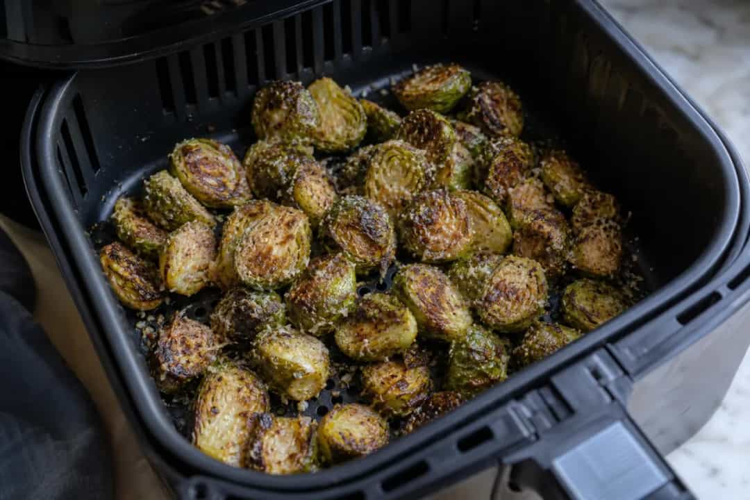 Crispy Brussels sprouts topped with Parmesan and balsamic glaze, plated attractively.