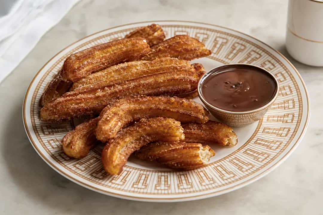 Golden-brown churros dusted with sugar, served with a rich chocolate dip