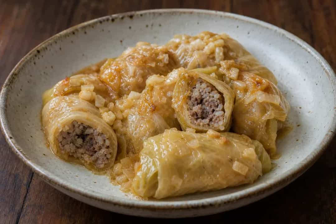 Plated Croatian sarma showcasing tender cabbage rolls filled with beef, rice, and topped with sauerkraut.