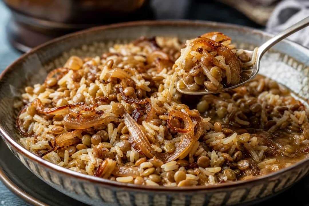 Bowl of mujadara with lentils and rice topped with crispy onions, garnished with fresh herbs.