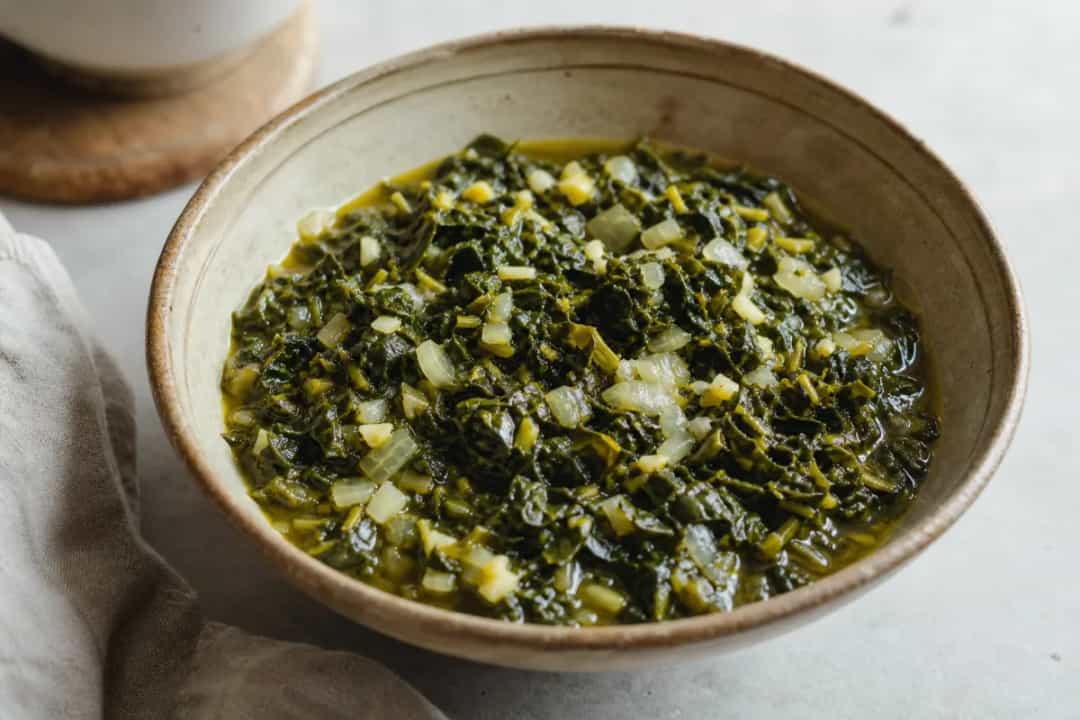 Plated Ethiopian Gomen with vibrant collard greens, garlic, and spices, garnished and served warmly.