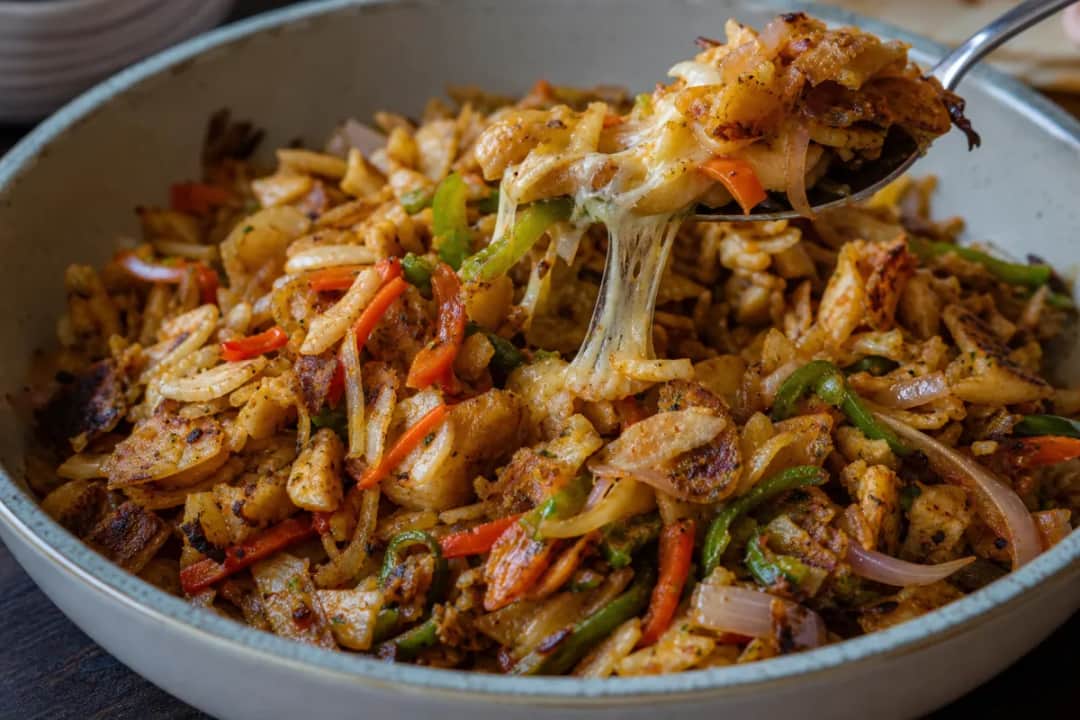 Plate of Sri Lankan Kottu Roti with chicken, shredded bread, and colorful vegetables.