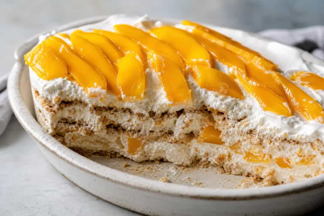 Layers of creamy mango float with graham crackers, garnished with mango slices.
