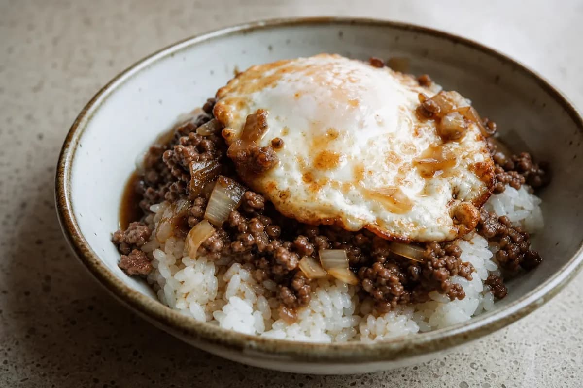 A hearty serving of Hawaiian loco moco with rice, a beef patty, brown gravy, and a perfectly fried egg on top.