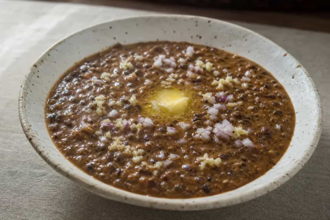 Creamy Indian dal makhani with black lentils, garnished with butter and cilantro, served in a bowl.