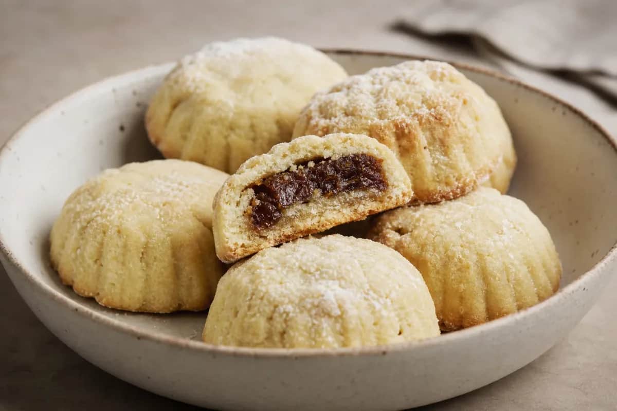 Golden-brown maamoul cookies filled with date paste, dusted with powdered sugar.