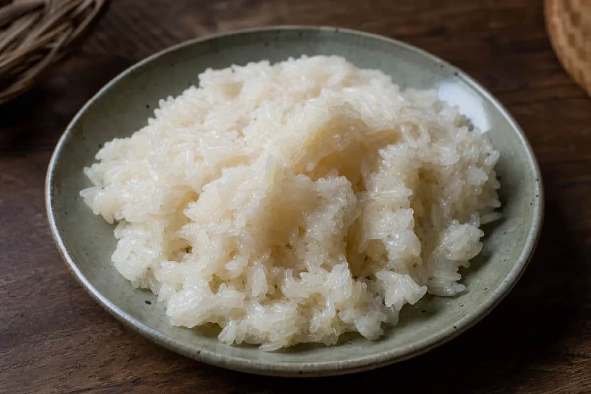Fluffy, glossy sticky rice served in a woven basket, showcasing its texture and simplicity.