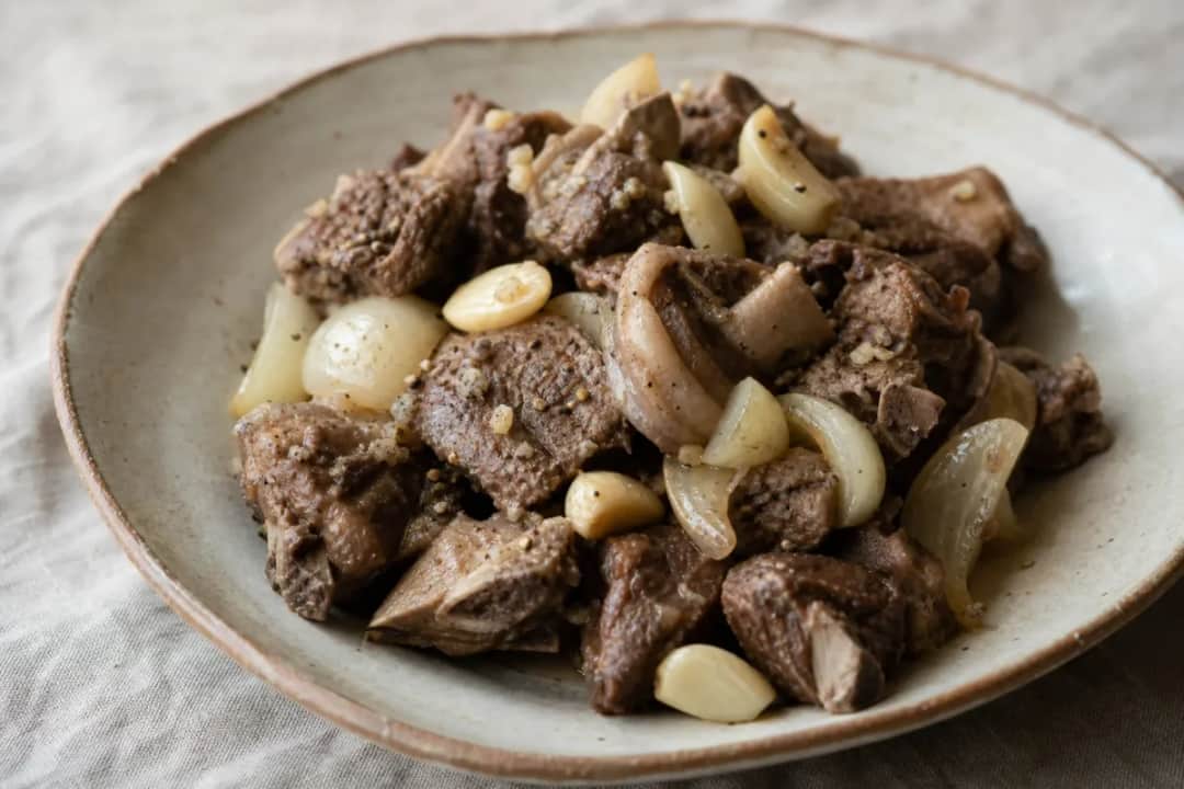 Tender slow-cooked lamb with spices, served with fresh vegetables on a rustic plate.