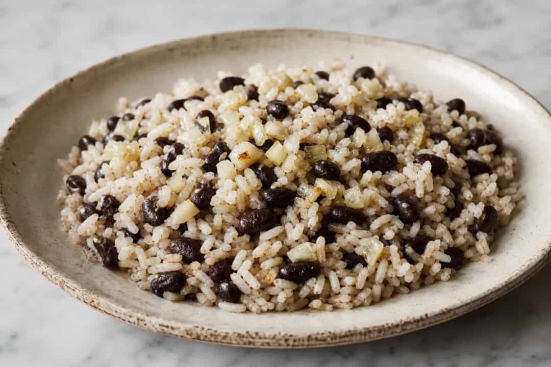 A vibrant plate of Moros y Cristianos featuring fluffy rice, black beans, and garnished with herbs.
