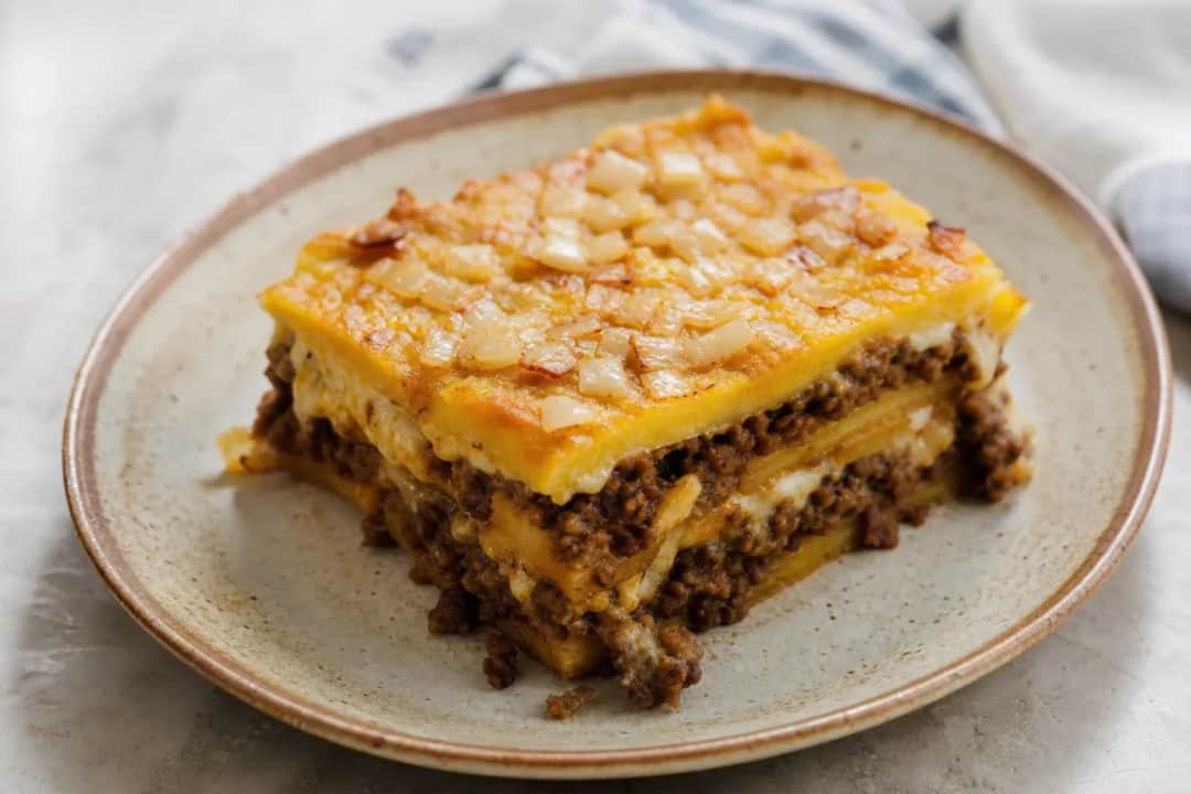 Layered pastelón featuring sweet plantains, ground beef, and melted cheese in a colorful presentation.