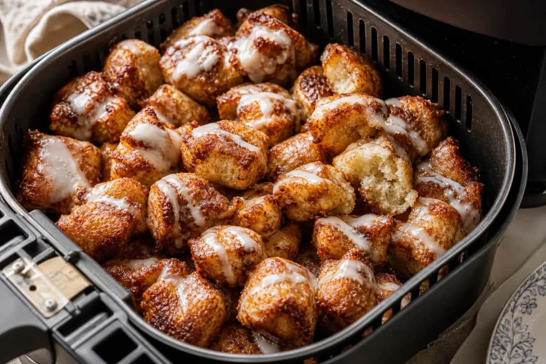 Plated air fryer cinnamon roll bites drizzled with warm vanilla glaze, showcasing their fluffy texture.