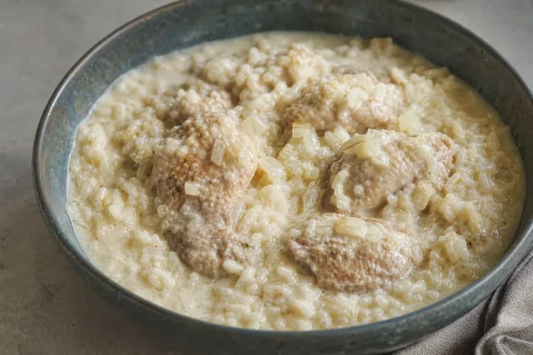 Creamy white rice topped with tender chicken pieces and garnished with herbs.