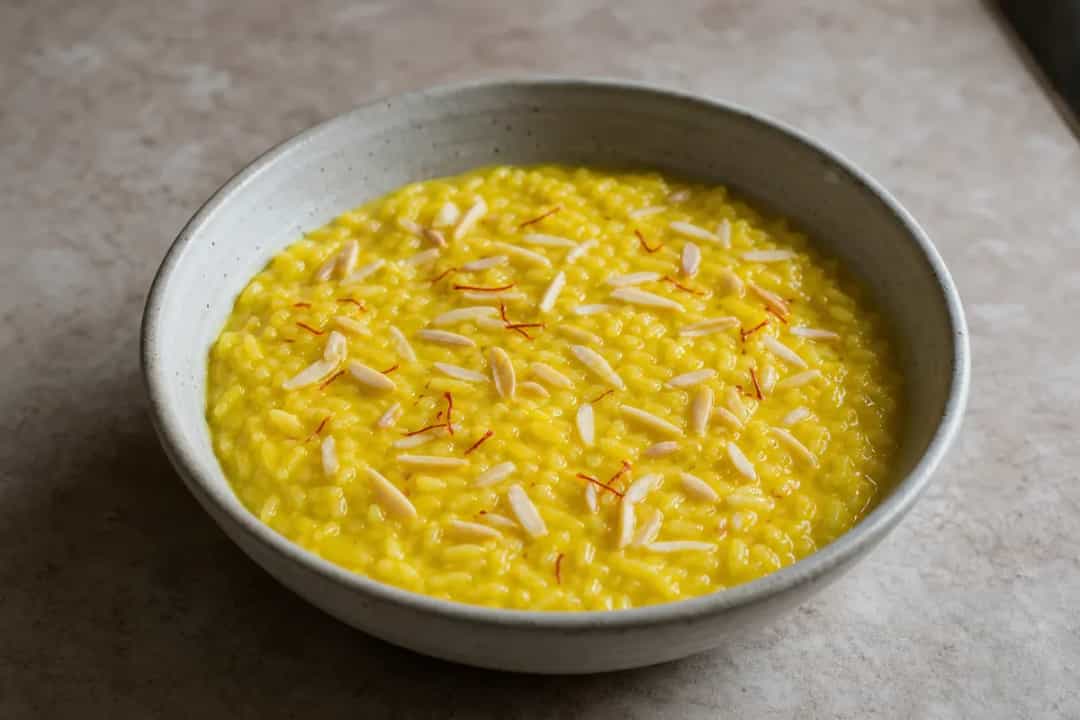 Creamy saffron rice pudding topped with almonds and cinnamon, served in a bowl.