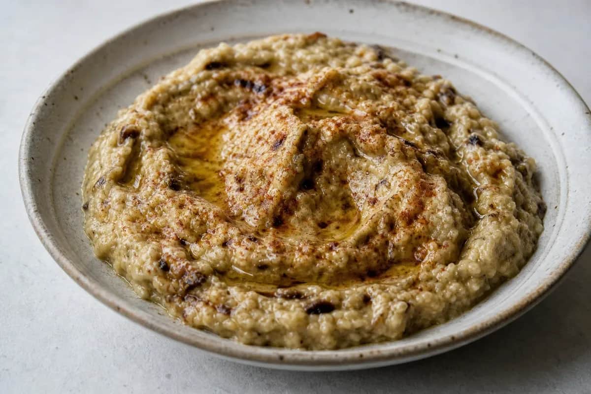 Creamy baba ganoush served in a bowl, garnished with olive oil and parsley.