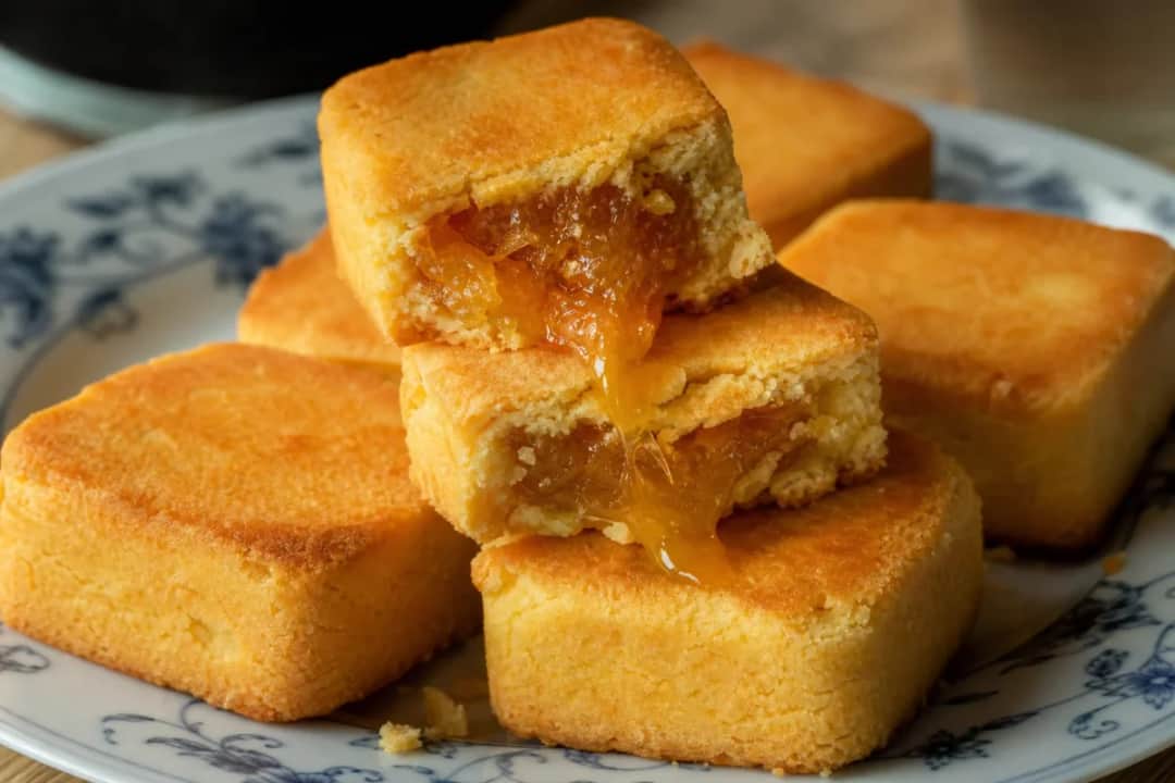 Plated Taiwanese pineapple cakes with a golden crust and sweet pineapple filling.