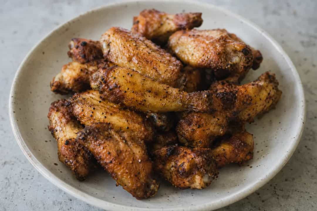 Golden brown airfryer chicken wings garnished with herbs, crispy texture.